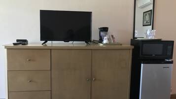 A kitchenette with a flat-screen TV, a coffee maker, a microwave, and a refrigerator.
