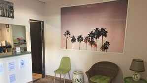 A reception area with a counter, chairs, a wall mural, and a small table with a lamp. - Luquillo Sunrise beach Inn (Luquillo)
