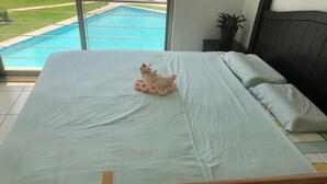A bedroom with a bed, a view of a swimming pool, and a wooden crib with toys. - Shanghai (Cancun)