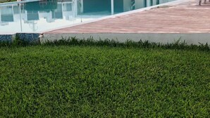 A swimming pool with a tiled edge and a grassy area in the foreground. - Shanghai (Cancun)