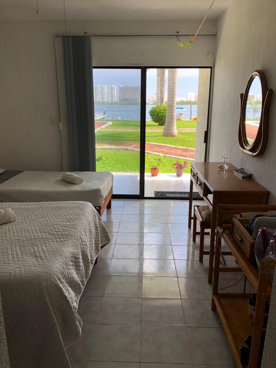 A hotel room with two beds, a desk, and a view of a body of water and greenery.