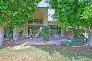 A patio with outdoor furniture, a large potted plant, and a building with large windows. - 258LQ  Located at PGA West at the TPC Stadium (La Quinta)