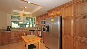 Une cuisine moderne avec des meubles en bois, des appareils électroménagers en acier inoxydable et une table en bois.
