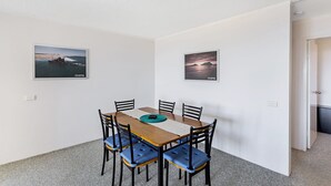 Een eethoek met een tafel, stoelen en twee ingelijste foto's aan de muur.