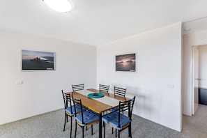 Un coin repas comprenant une table, des chaises et deux tableaux encadrés accrochés au mur.