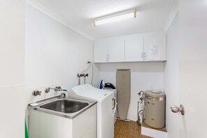 A compact laundry room with a washing machine, dryer, and a water heater.