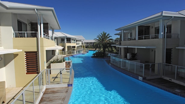 Un hôtel moderne doté d’une piscine centrale, de nombreux balcons et offrant une vue sur un ciel d’un bleu éclatant.