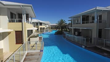 Una piscina con cubierta de madera, rodeada de edificios modernos con balcones y barandillas.