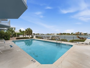 A rectangular pool with a 6 FT depth marker, surrounded by lounge chairs and a railing, with a view of buildings and a body of water in the background. - Amadeus 9 - Direct Waterfront Views in top location! (Treasure Island)