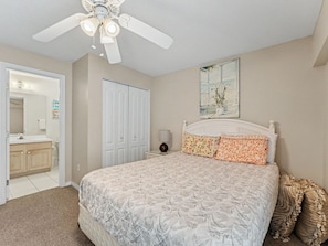 A bedroom with a bed, a ceiling fan, a nightstand, a lamp, a painting, and a wardrobe. - Amadeus 9 - Direct Waterfront Views in top location! (Treasure Island)