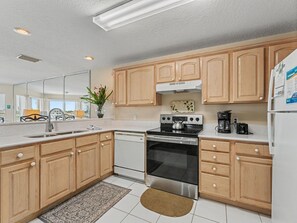 A modern kitchen with wooden cabinets, a stainless steel stove, a dishwasher, and a refrigerator. - Amadeus 9 - Direct Waterfront Views in top location! (Treasure Island)
