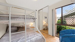 Habitación con literas y vista a un jardín a través de un vidrio.