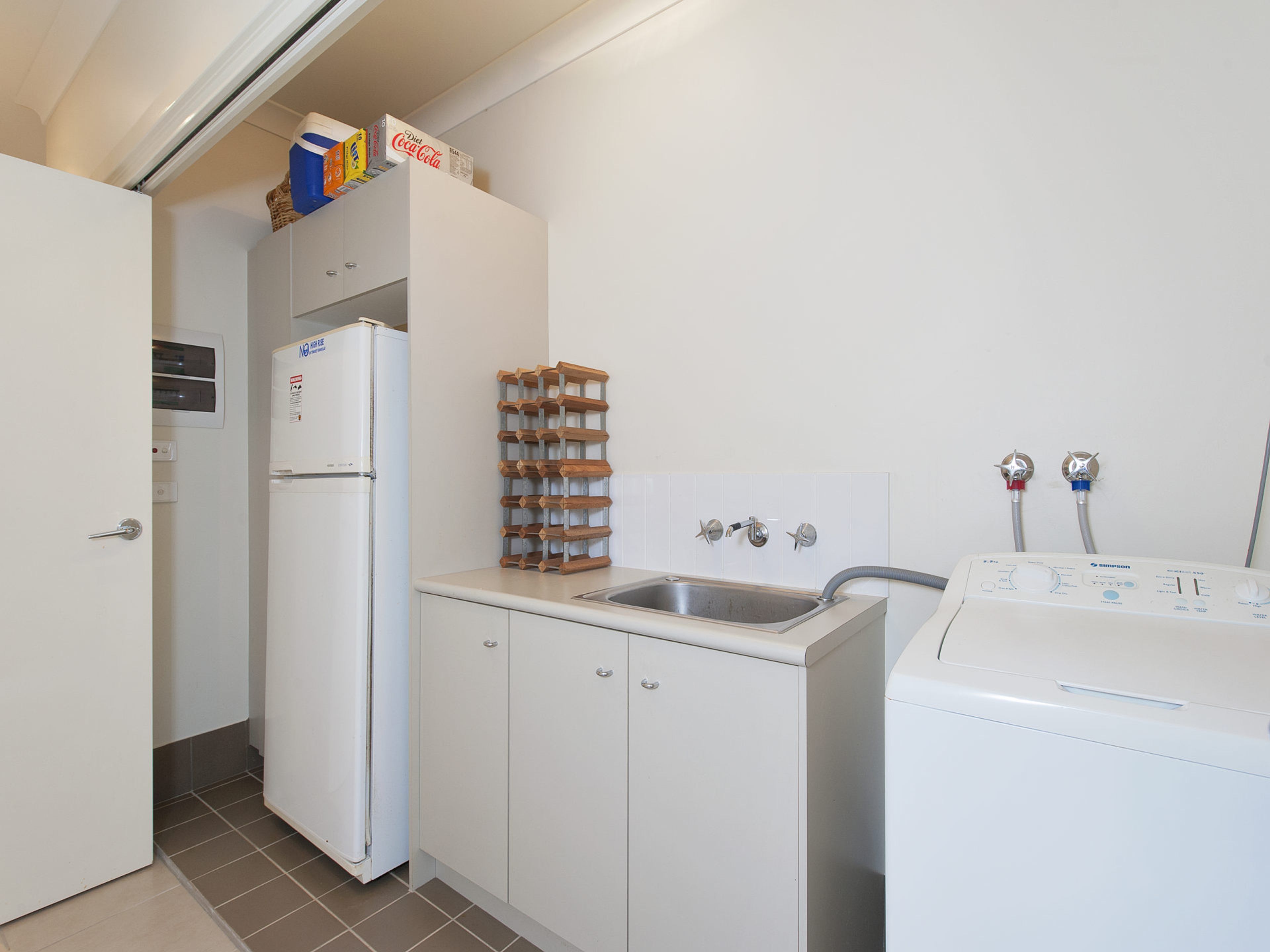 A compact kitchen with a refrigerator, a sink, and a washing machine.