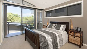 Une chambre à coucher comprenant un lit, une table de chevet, une lampe, un ventilateur de plafond et une vue sur l’extérieur.