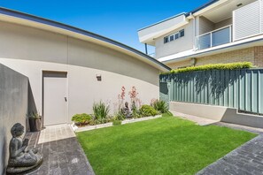A modern residential building with a curved facade, a small lawn, and a statue. - Fingal Surf and Sand Pet Friendly with views (Fingal Bay)
