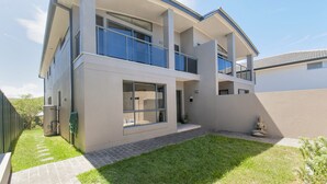 Une maison moderne à deux étages, dotée d’un toit plat, de grandes fenêtres et d’un balcon.