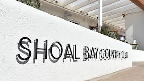 A white wall with the text 'SHOAL BAY COUNTRY CLUB' in black letters.