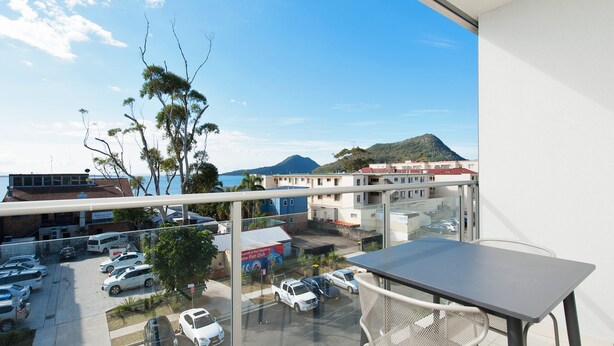 Varanda com vista para um estacionamento e edifícios, incluindo um restaurante.