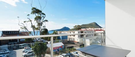 A balcony with a view of a parking lot and buildings, including a restaurant.