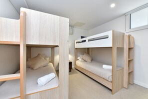 A bunk bed room with a wooden frame, a small bedside table, and a wall-mounted air conditioning unit.