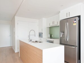 A modern kitchen with white cabinetry, stainless steel appliances, and a wooden countertop.