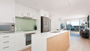 A modern kitchen with white cabinetry, stainless steel appliances, and a large island with a sink.