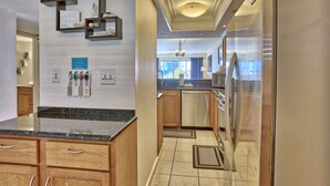 A modern kitchen with wooden cabinets, a granite countertop, and stainless steel appliances. - Land's End 302 building 5 Beautiful Updates | Stunning views | Unique Floor Plan (Treasure Island)