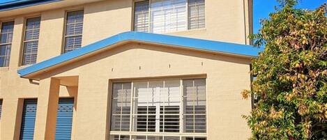 A building with a beige facade, large windows, and a blue awning.