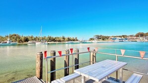 Vista nítida d'una marina amb vaixells, un moll de fusta i una taula amb bancs.