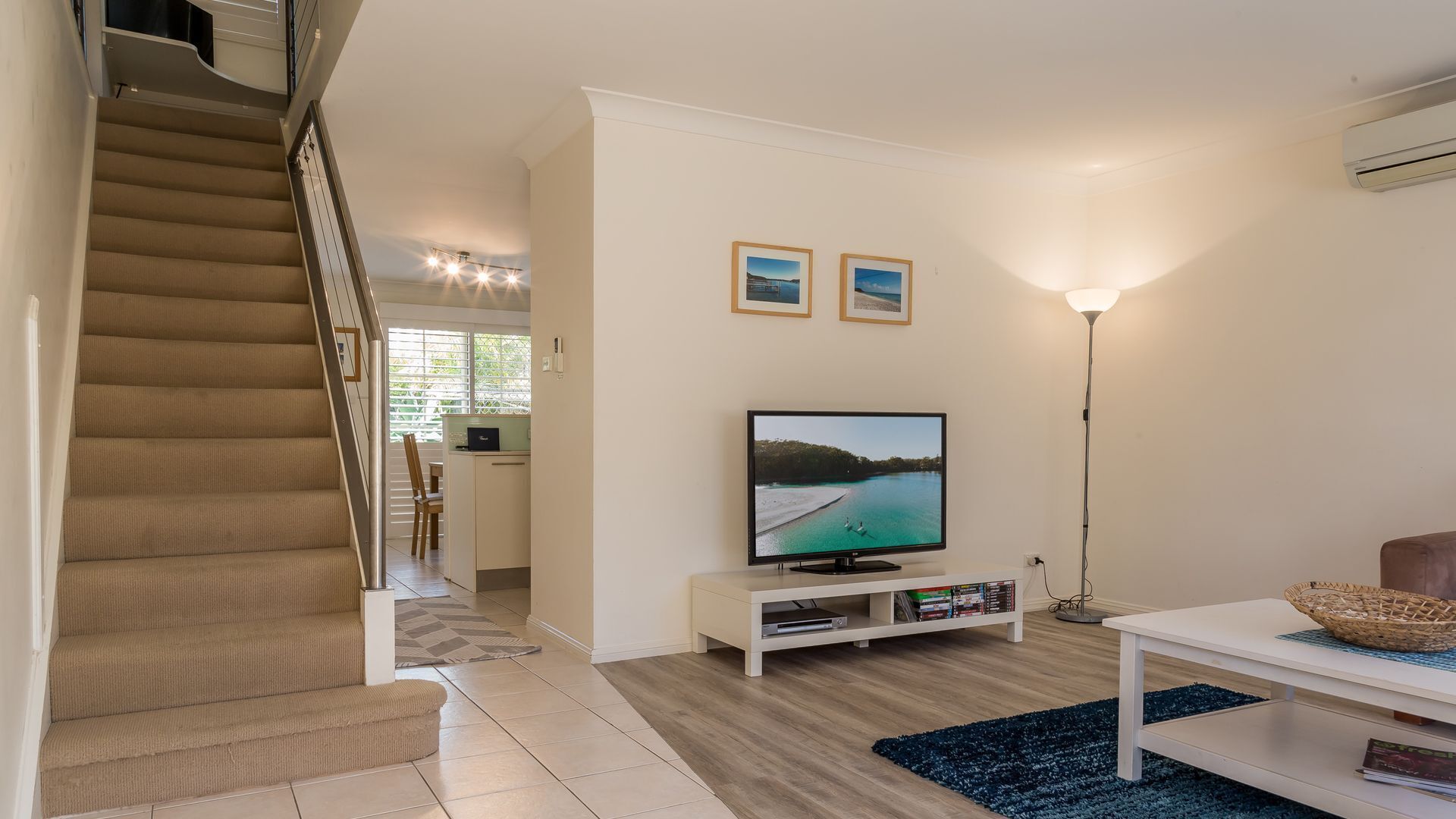 A living room with a TV, a staircase, and a dining area.