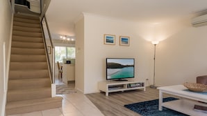 Un saló amb televisió, una escala i una zona de menjador.
