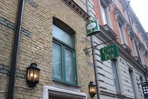 Um edifício de tijolos com uma placa verde que diz "City Pub" e uma janela com moldura branca.