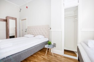 Un dormitorio con cama, una mesita de noche con una planta, un armario y una puerta que da a un baño.
