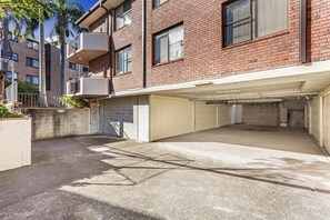 Un edificio de varios pisos de ladrillo con estacionamiento techado y un pequeño balcón.