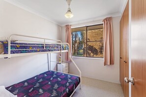 A room with bunk beds, a window with curtains, a door, and a ceiling light.