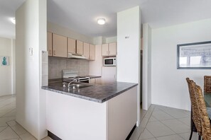 A modern kitchen with a central island, stainless steel appliances, and light-colored cabinetry.