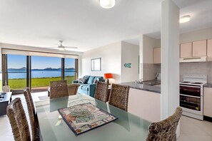 A modern kitchen with a built-in oven and a dining area with a glass table and wicker chairs.