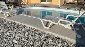 A pool area with lounge chairs and a building with a sliding glass door. - water front,pool,hot tub,fishing,close to beaches (new port richey)