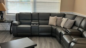 A modern living room with a sectional sofa, a coffee table, and a lamp. - water front,pool,hot tub,fishing,close to beaches (new port richey)