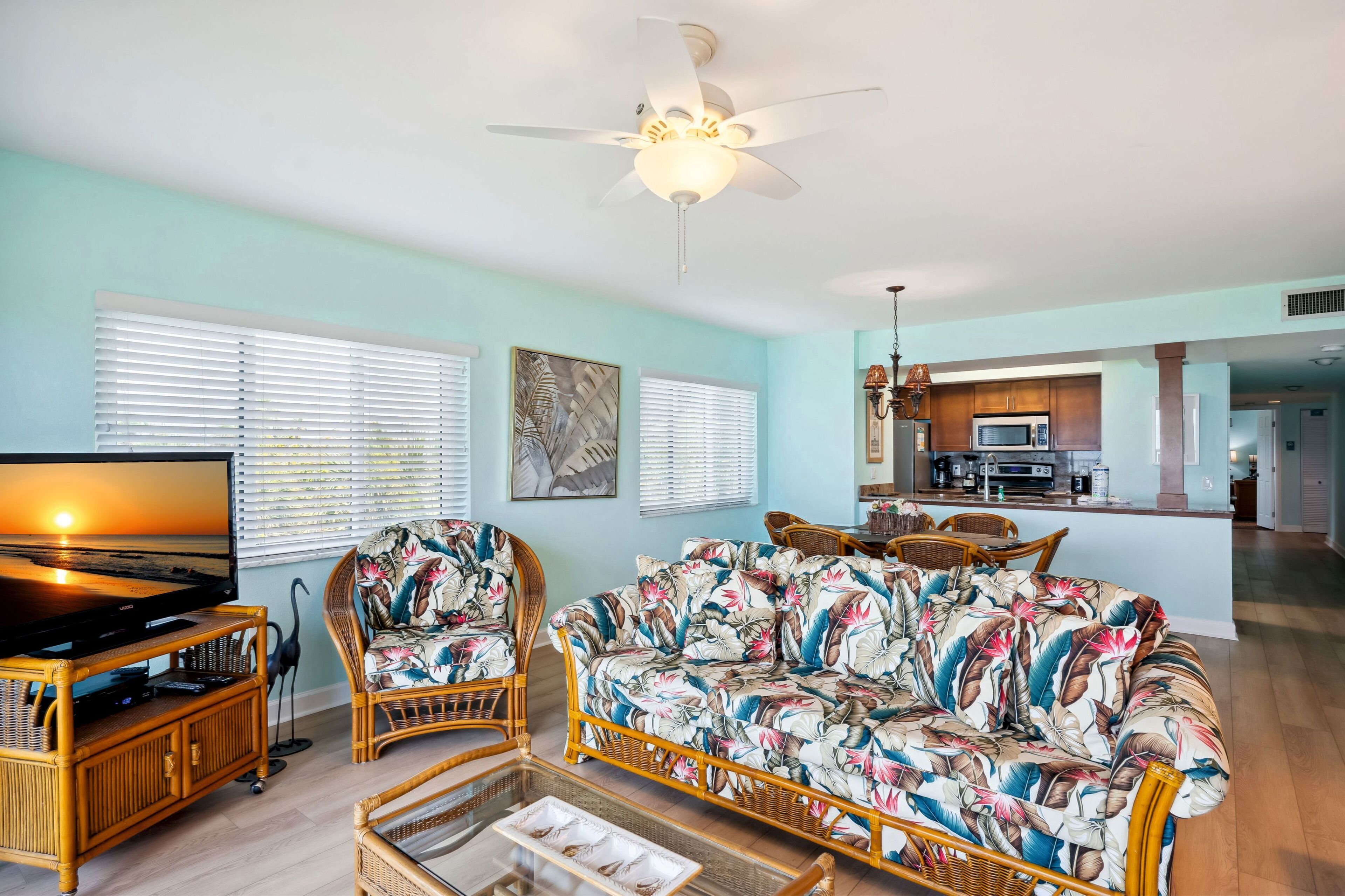 A living room with a sofa, chairs, a TV, and a ceiling fan.