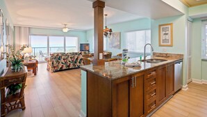 A spacious kitchen with a central island, wooden cabinets, and a large window providing natural light.