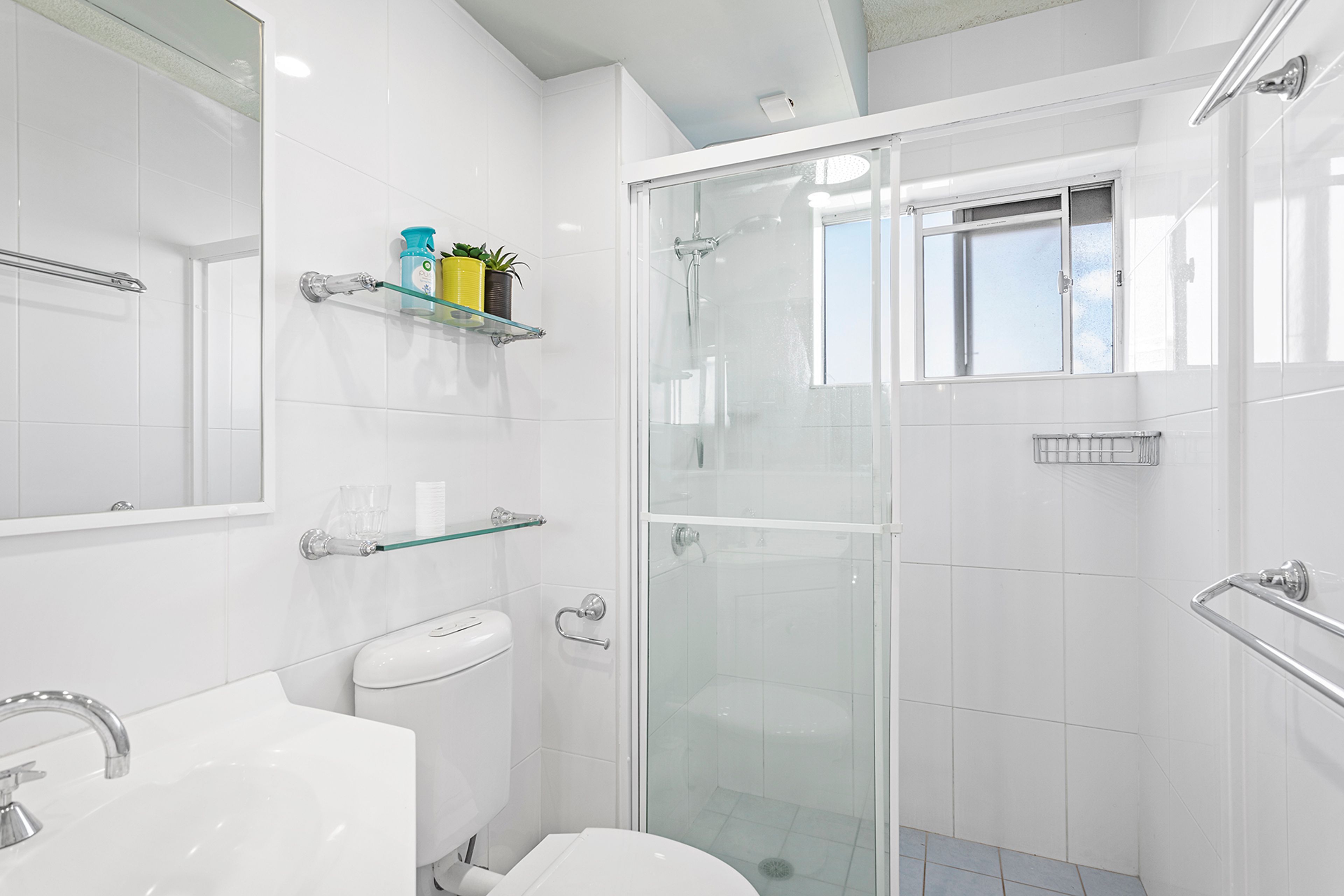 A modern bathroom with a glass-enclosed shower, a toilet, and a sink.