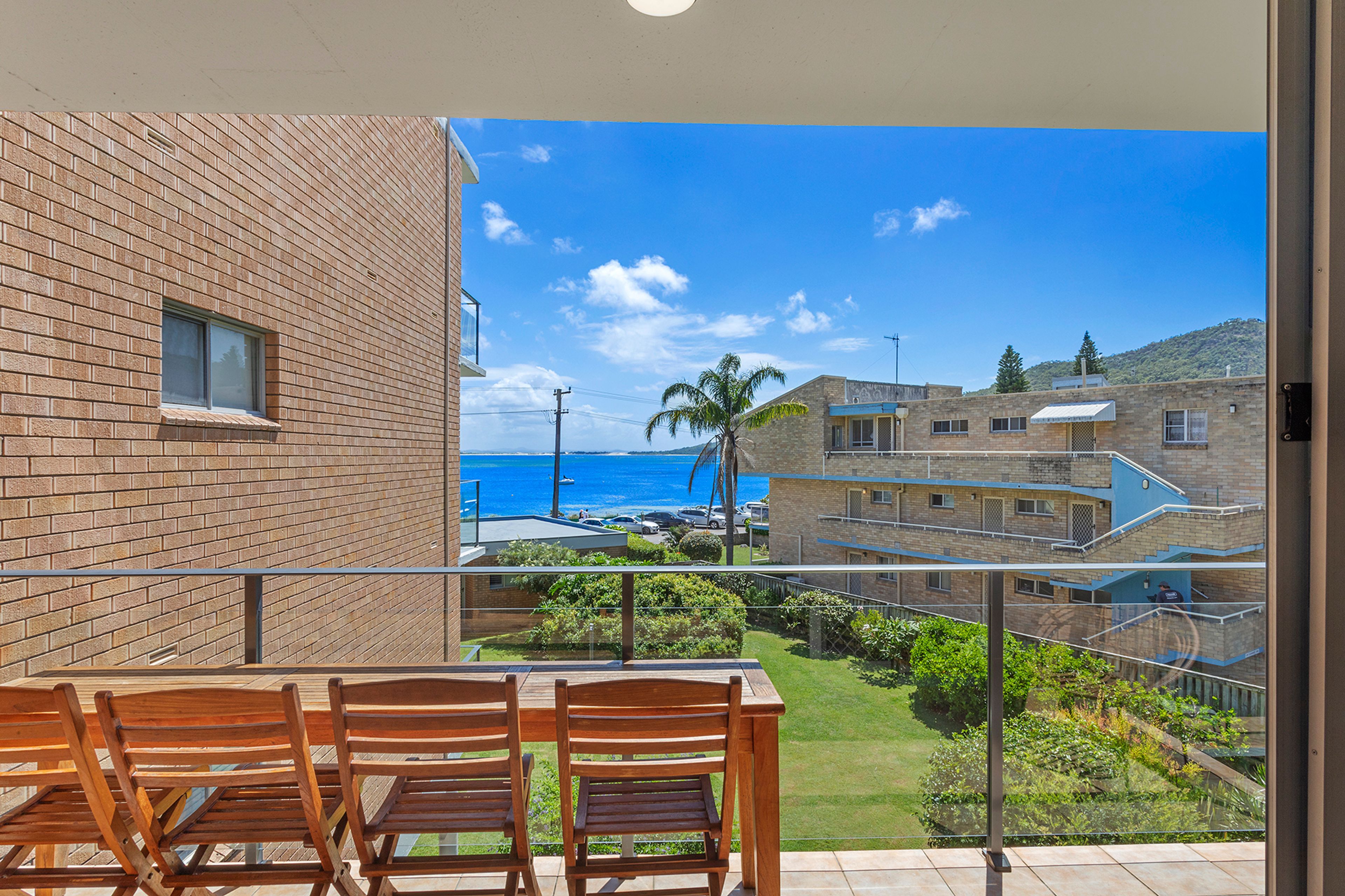 A balcony with a view of the sea and a building with a brick facade.
