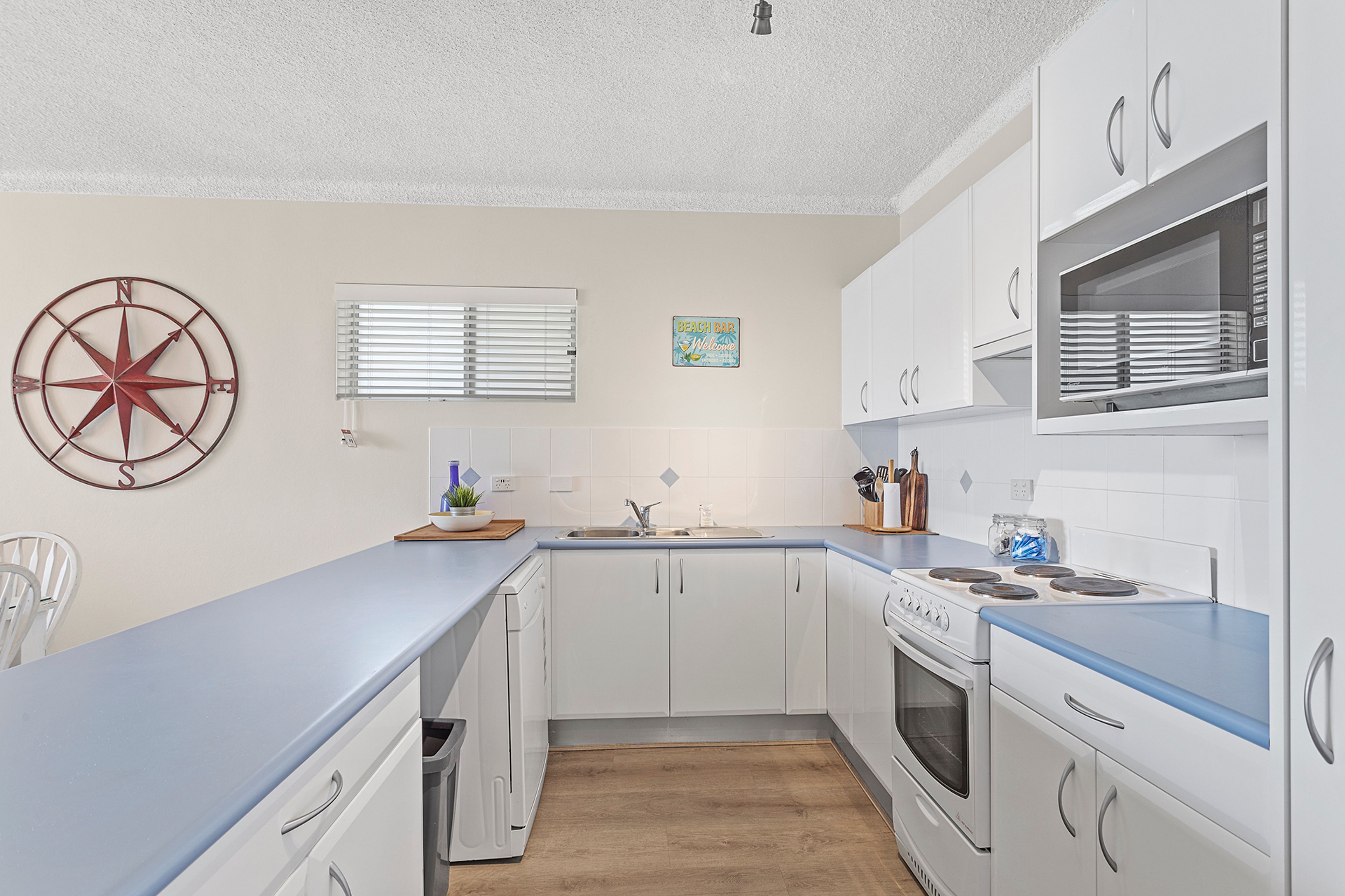 A kitchen with white cabinets, a blue countertop, a stove, and a sink.