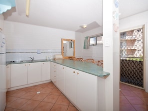 A kitchen with white cabinets, a green countertop, and a tiled floor. - Castaways 4 Shoal Bay Apartment with Water Views (Shoal Bay)
