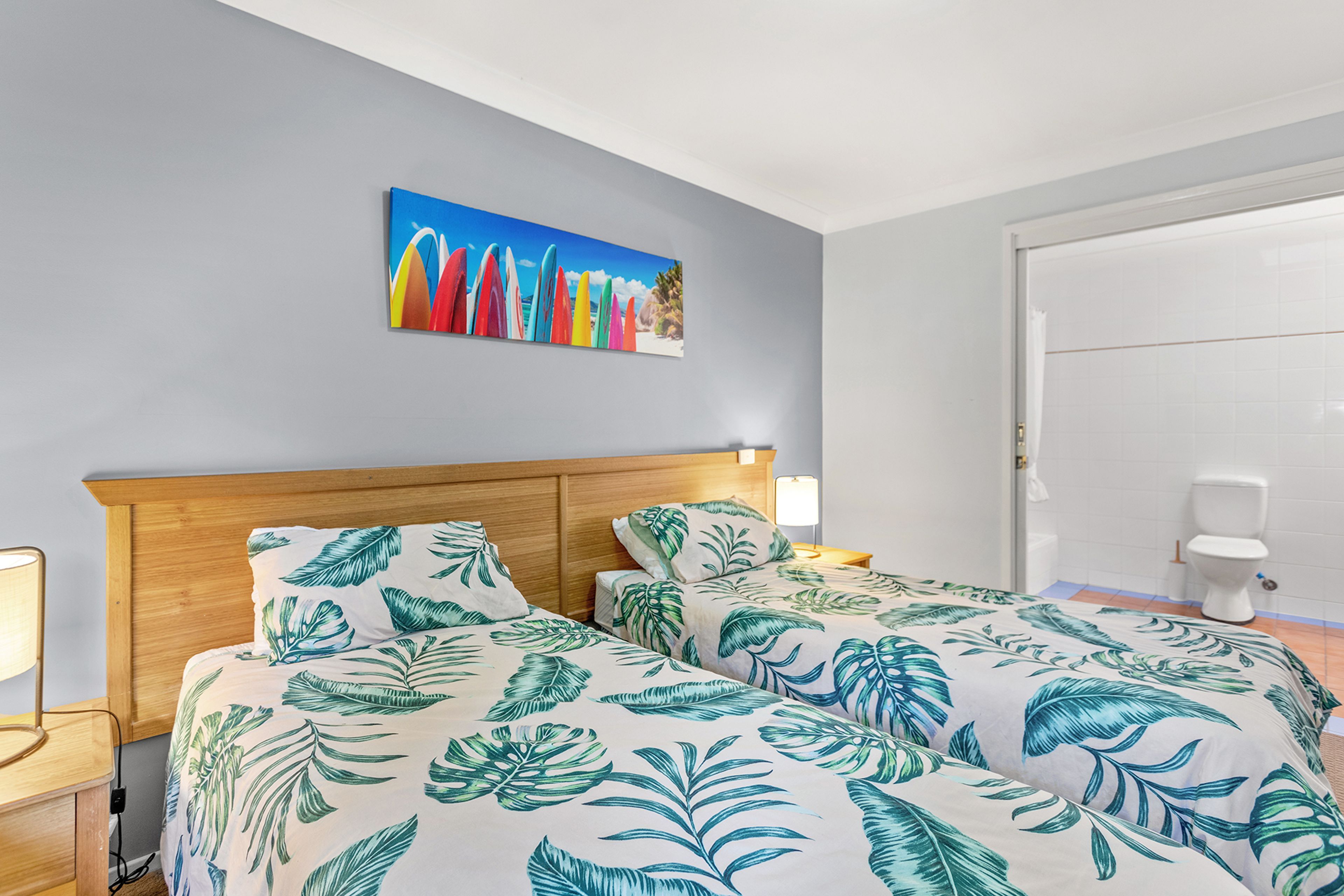A hotel room with a bed, a nightstand, a lamp, and a painting on the wall.