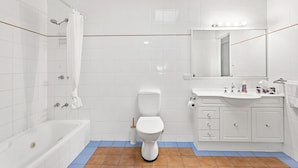 Een badkamer met een bad, toilet, wastafel en spiegel.