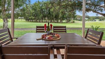 An outdoor wooden table set for a meal with a view of a grassy area and trees.
