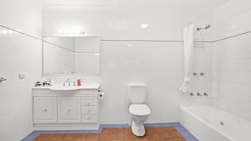 Une salle de bain avec un lavabo, des toilettes et une baignoire, le tout de couleur blanche.