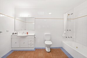 Un baño con lavamanos, inodoro y bañera blancos.